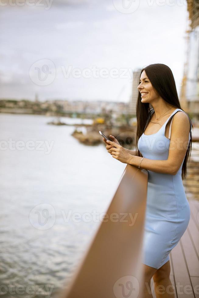 jovem usando um telefone celular em pé no calçadão do rio foto