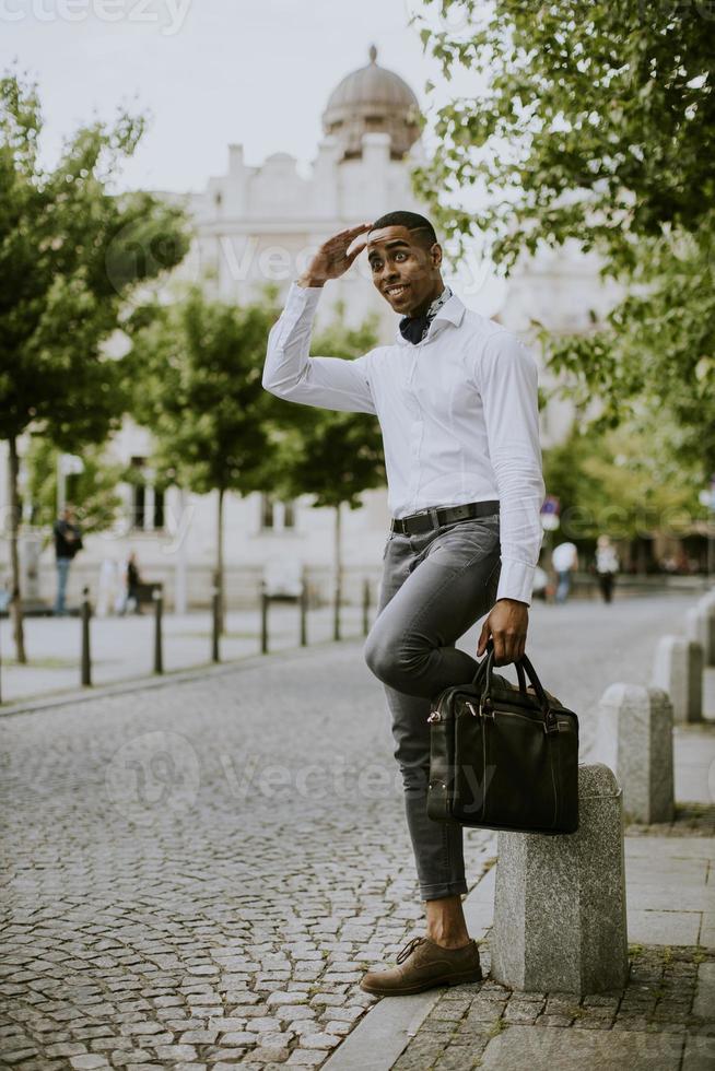jovem empresário afro-americano esperando um táxi em uma rua foto