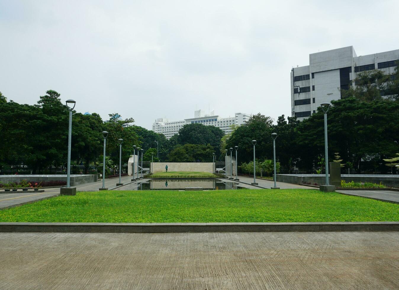 Visão do pessoas rega a jardim quintal. isto parque é cercado de vegetação e de várias jardim postes de iluminação foto