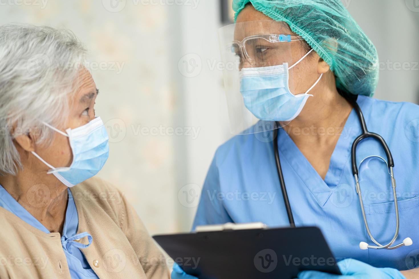 médico asiático usando protetor facial e terno novo normal para verificar paciente proteger segurança infecção covid 19 surto de coronavírus na enfermaria de quarentena do hospital foto