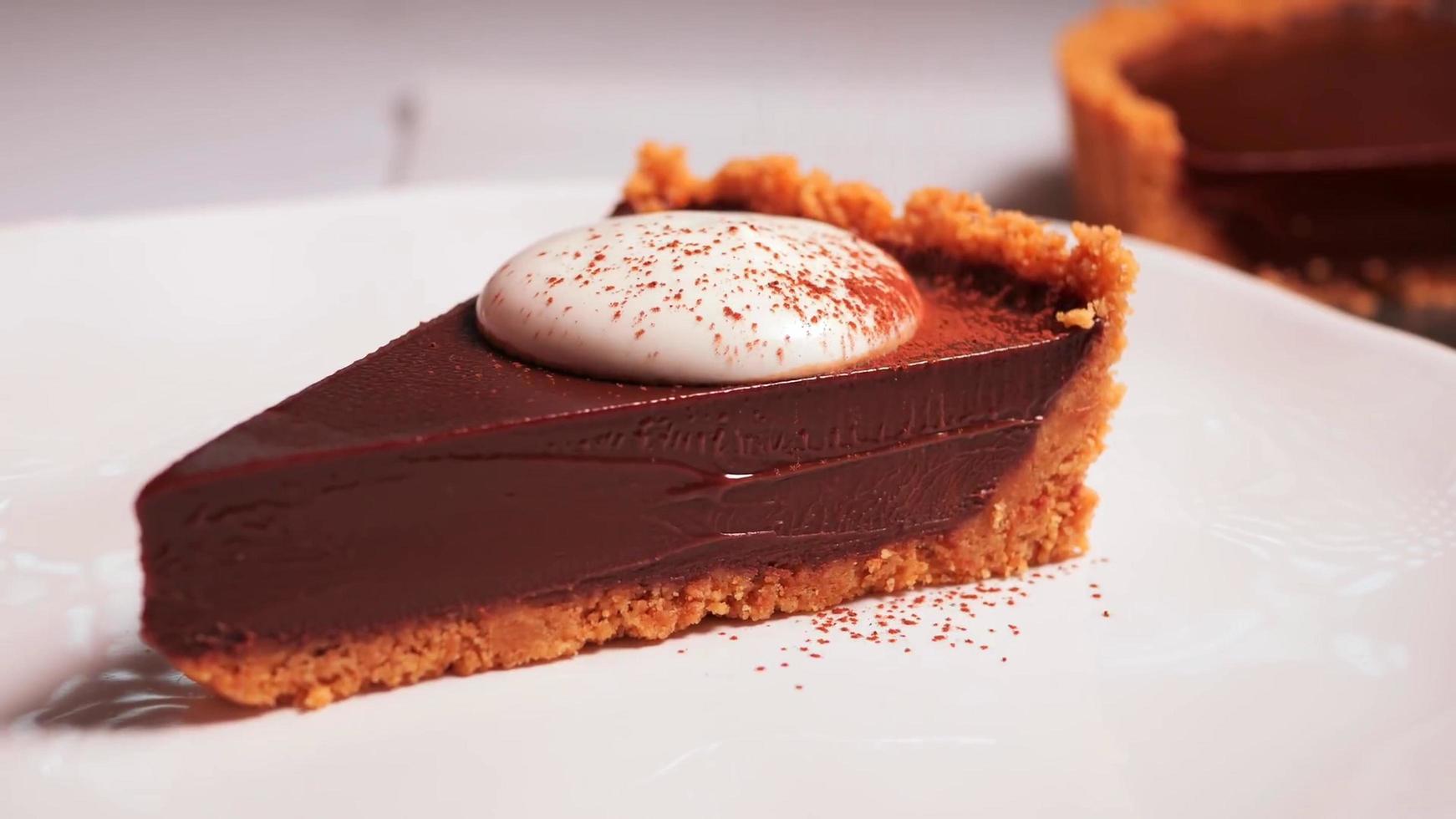 fotografia de close de um pedaço de bolo de chocolate com creme branco em um prato branco foto