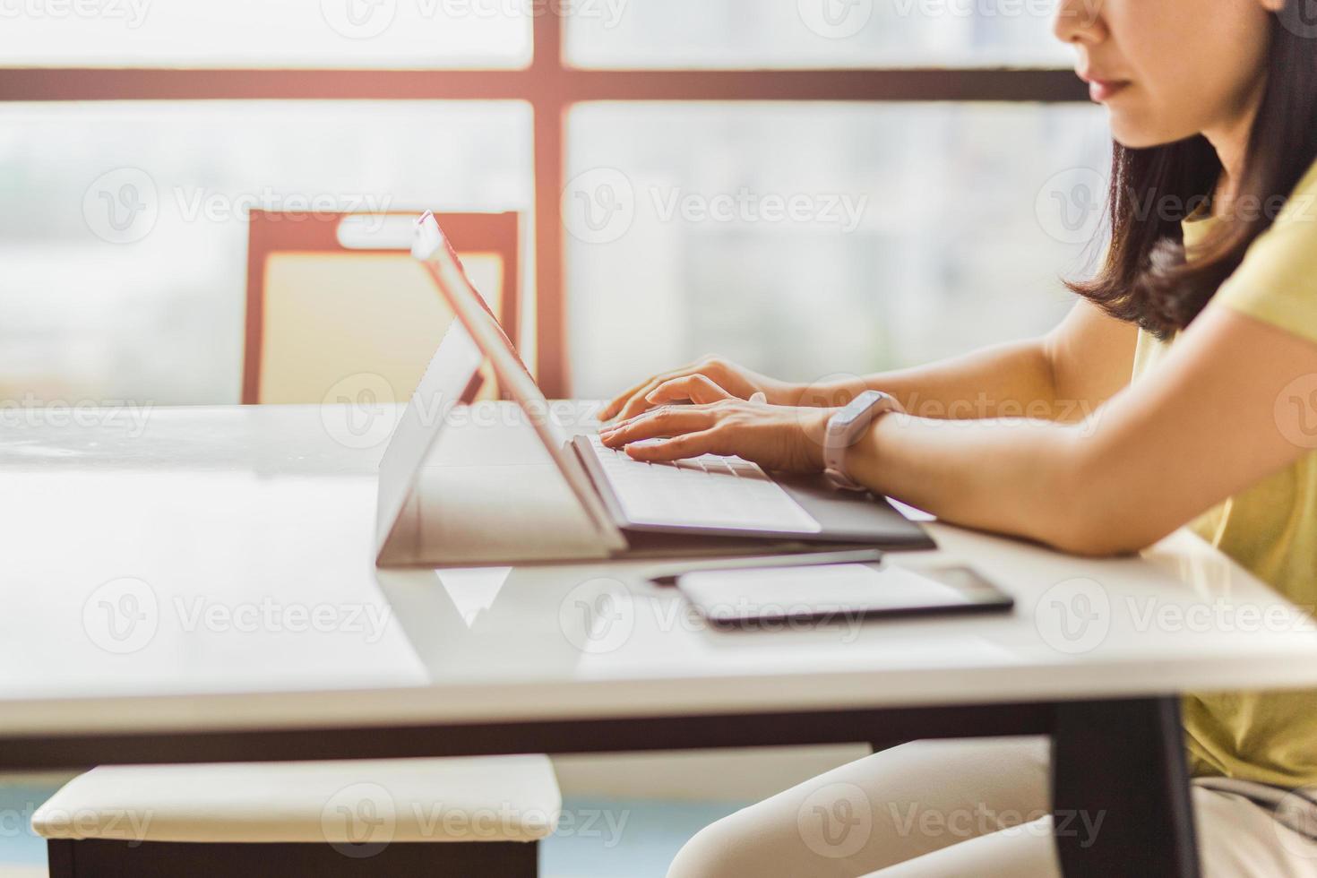 mulher trabalhando em casa, no escritório, digitando no teclado do computador foto