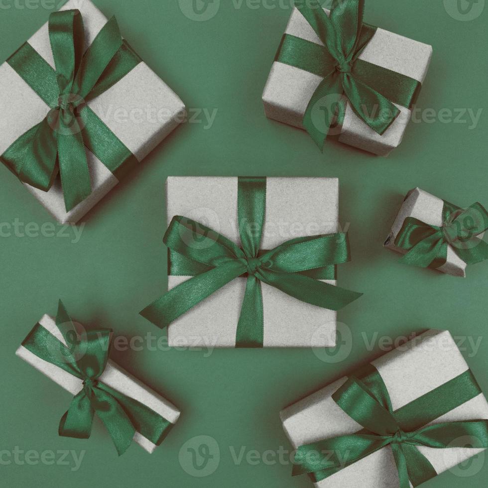 caixas de presente embrulhadas em papel artesanal com fitas verdes e laços festivos monocromáticos plana lay foto