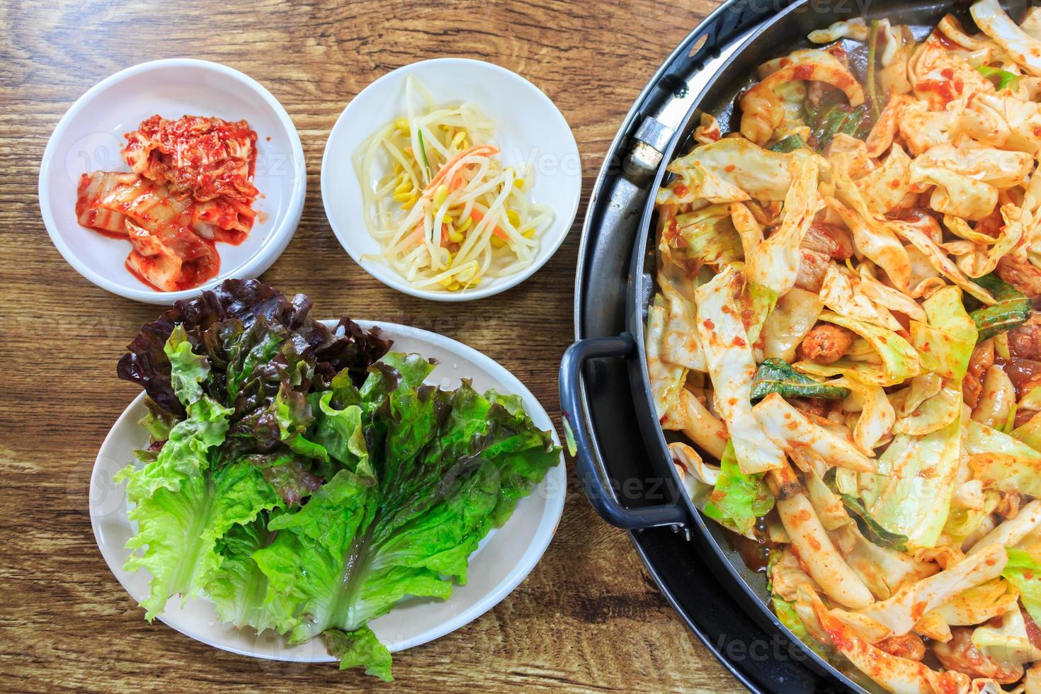 comida coreana composta por brotos de feijão de alface kimchi e vegetais fritos com frango na mesa de madeira foto