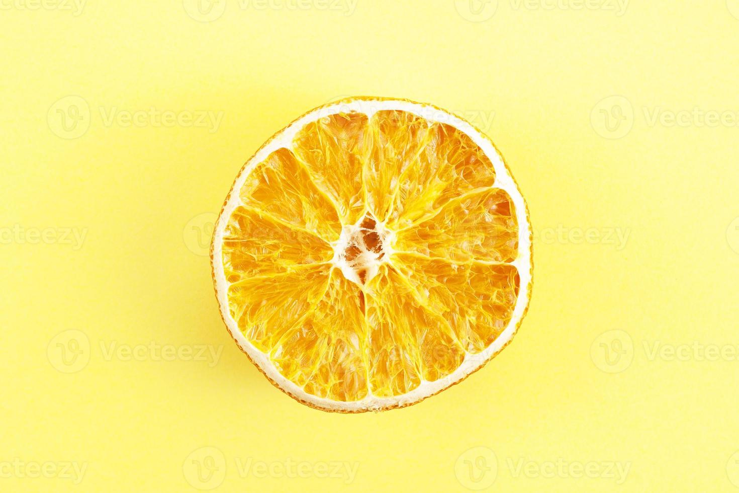 um pedaço de laranja seca em fundo amarelo foto