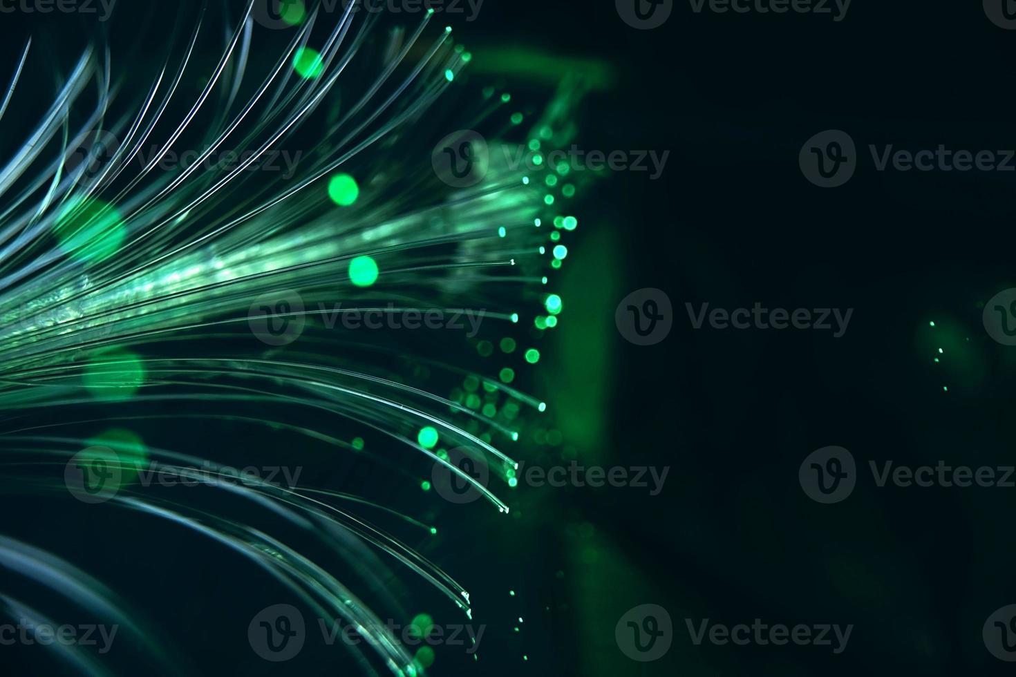 uma macro incrível e vibrante de tubos de fibra ótica verdes que iluminam fazendo brilhos e brilhos com fundo preto foto