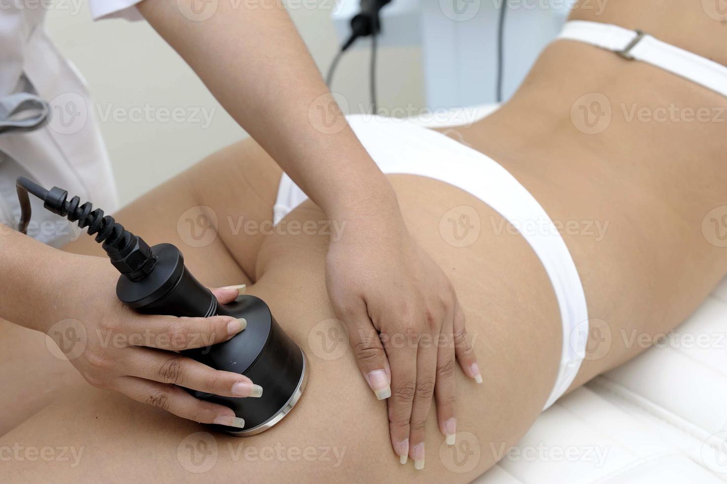 Close de cosmetologia de esteticista fazendo tratamento de depilação a laser no lindo corpo feminino, removendo pelos na pele sedosa foto