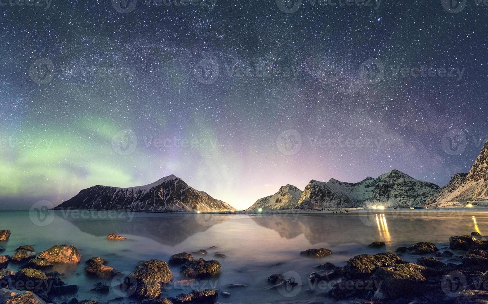 panorama da aurora boreal com a Via Láctea sobre a montanha de neve na costa foto