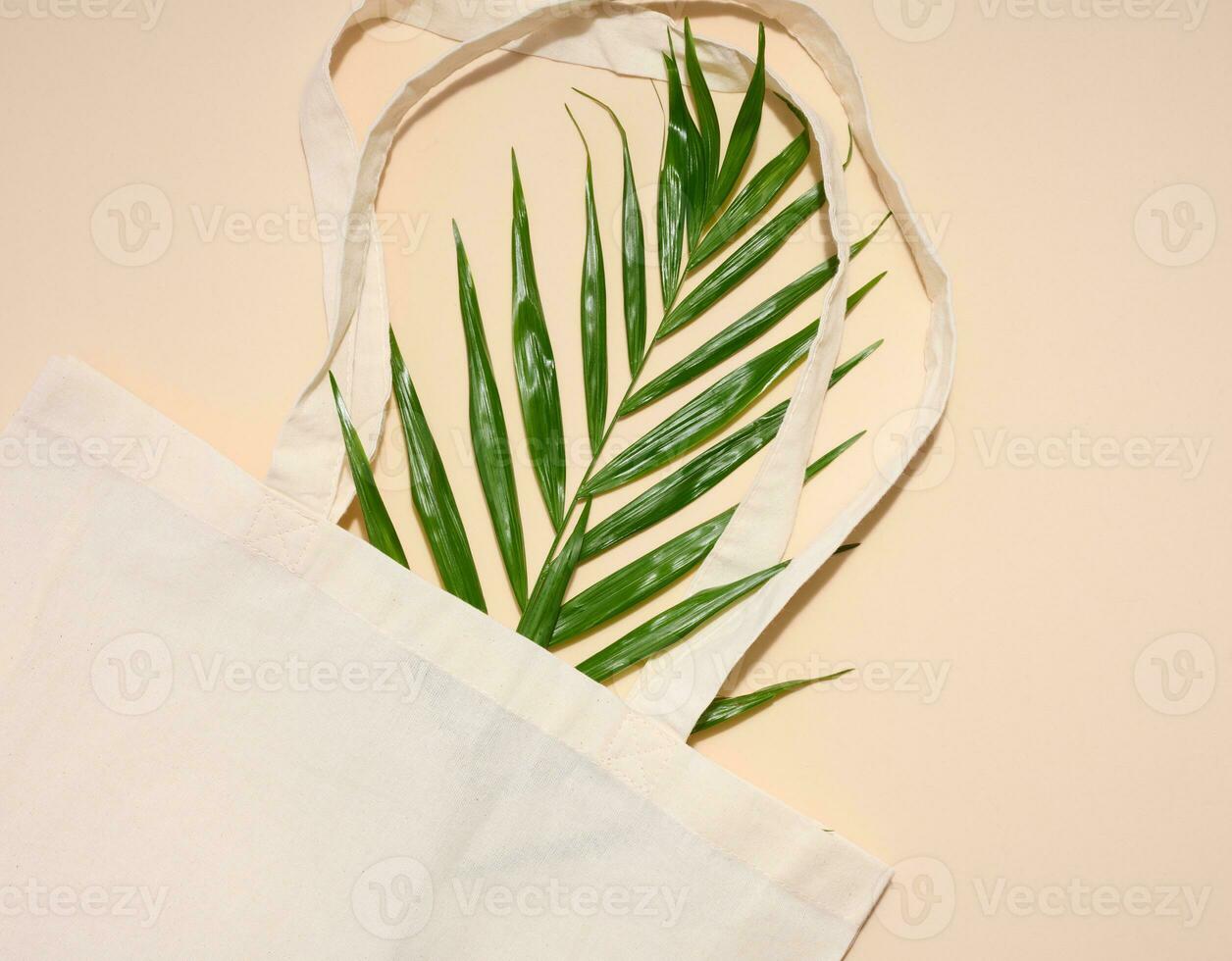 esvaziar têxtil saco e verde Palma folha em bege fundo, topo Visão foto