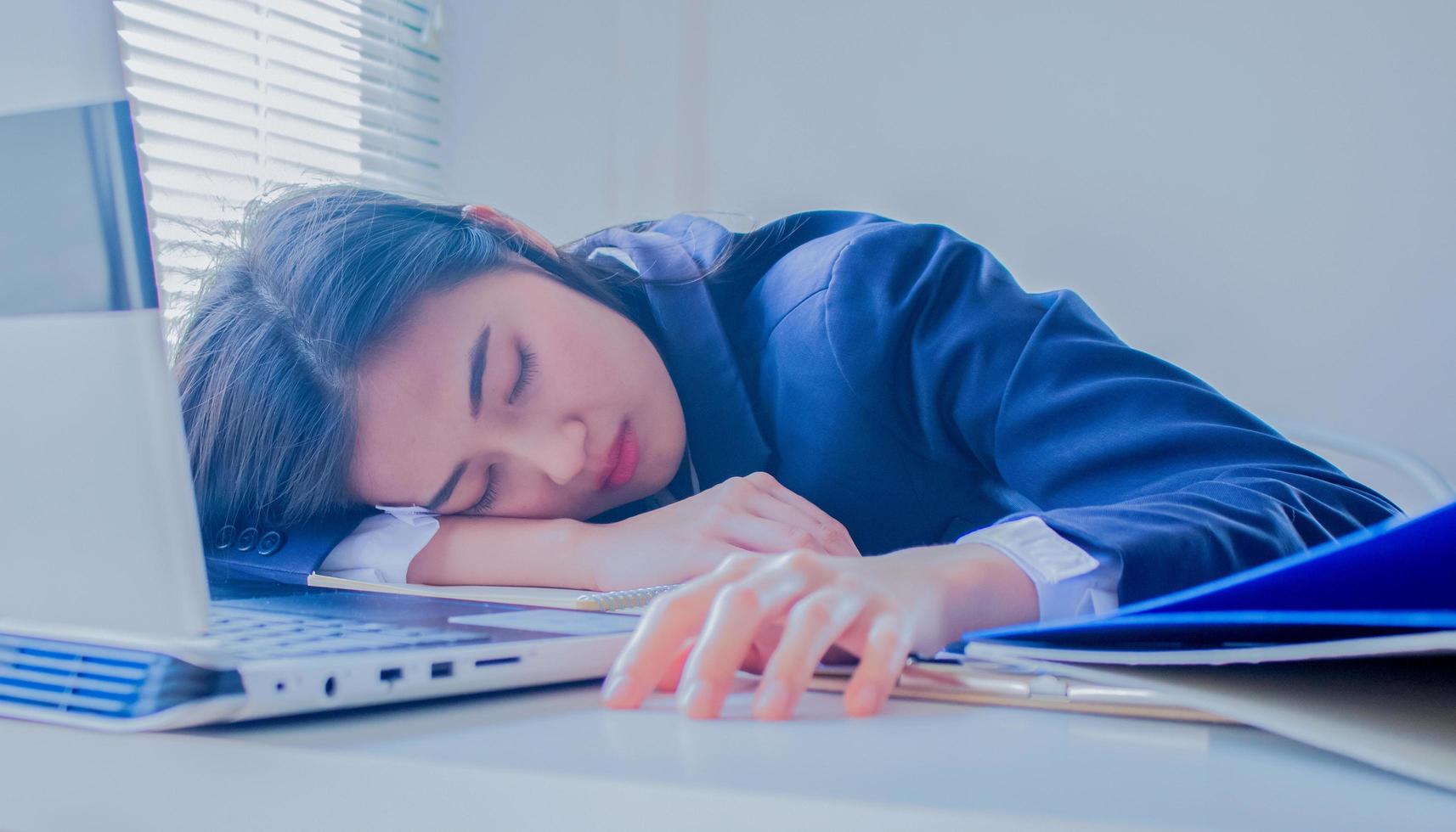 retrato de uma jovem mulher de negócios asiática dormindo na mesa, cansado foto