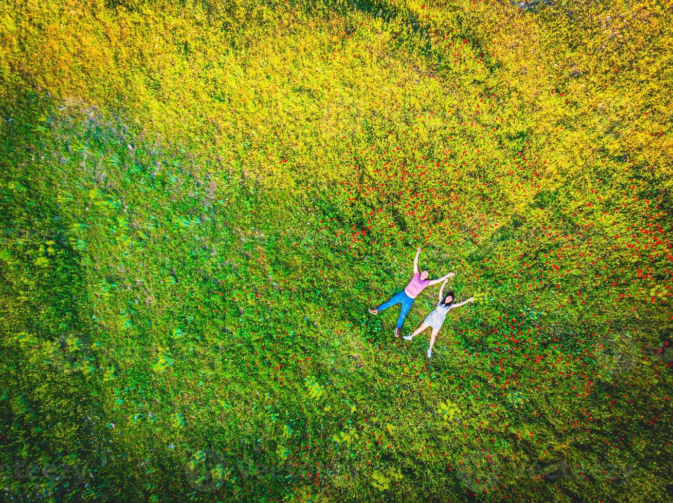 vista superior de um casal feliz deitado ao ar livre em um campo verde de verão foto