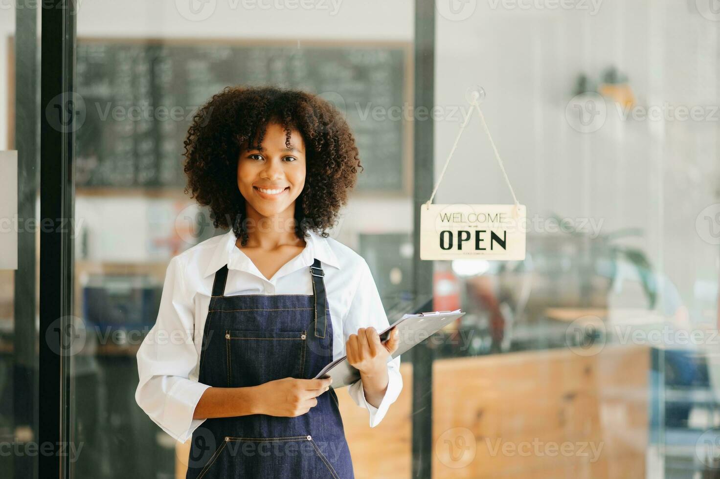 comece bem sucedido pequeno o negócio proprietário sme africano mulher ficar de pé com tábua dentro cafeteria restaurante. mulher barista cafeteria proprietário. foto