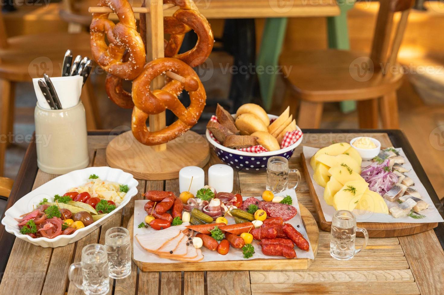 salsichas com queijo e pepinos fermentados, salgadinhos de pretzel com vodka na mesa foto