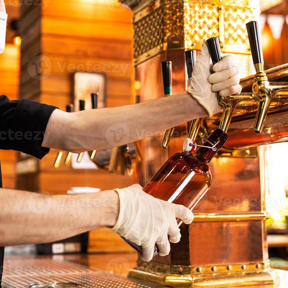 homem servindo e enchendo uma caneca de vidro de cerveja foto