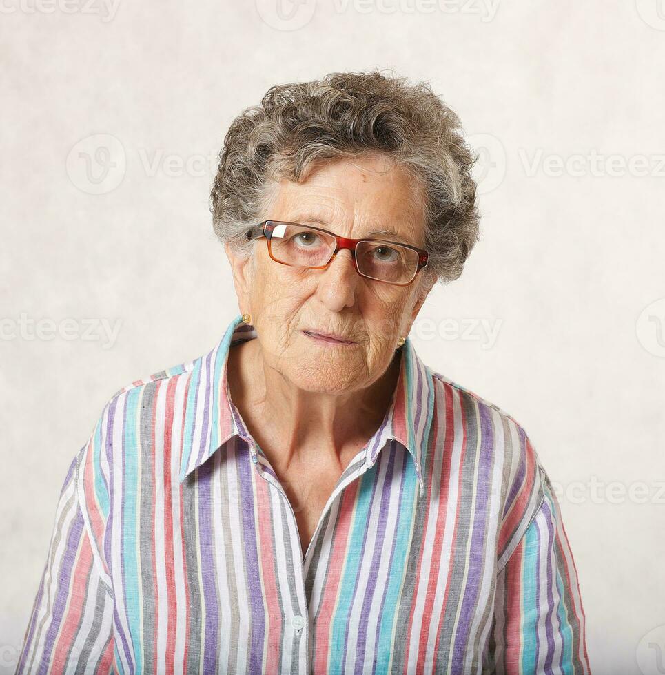 uma reflexivo Senior mulher. cinzento fundo foto