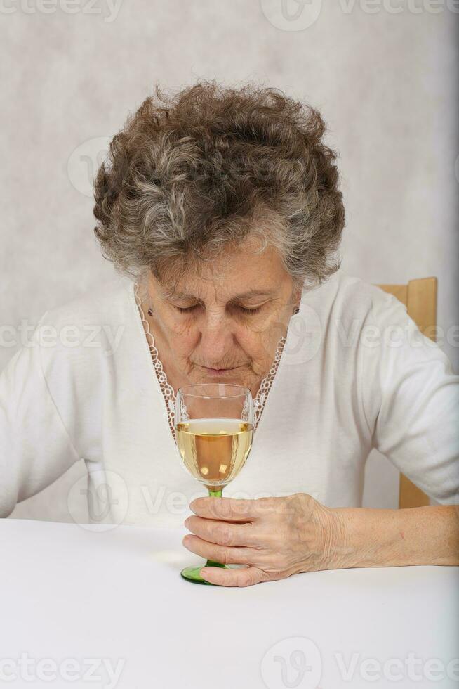Senior mulher é sobre para beber uma vidro do branco vinho foto
