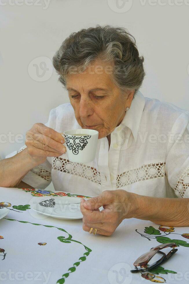 a velho mulher é levando uma copo do chá foto
