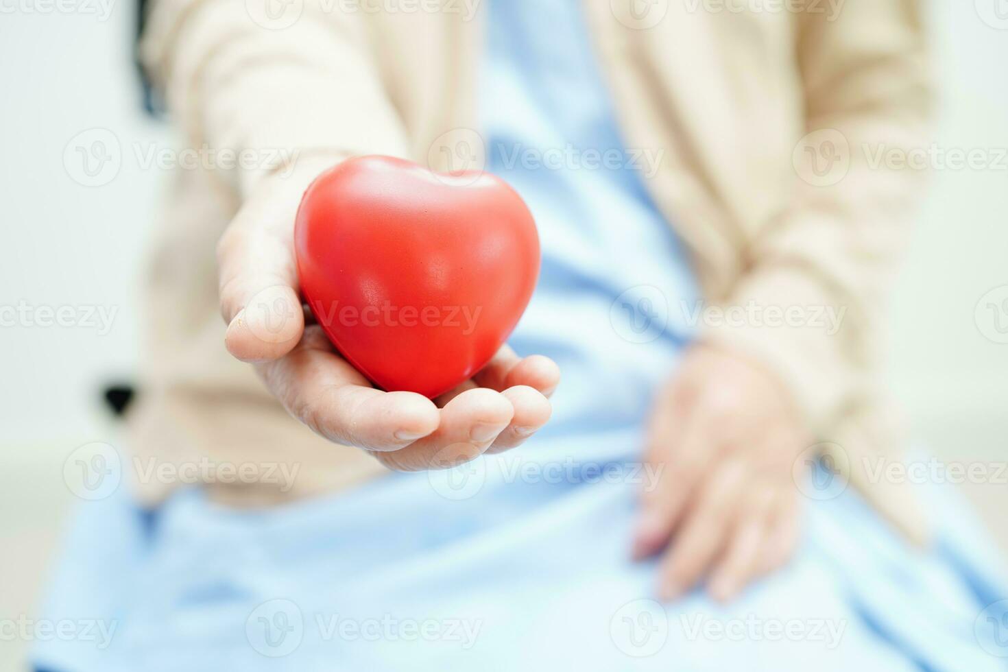 paciente asiática idosa idosa segurando coração vermelho no hospital. foto