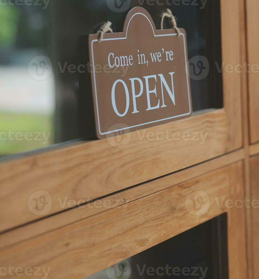 bem-vinda. abrir. barista, garçonete mulher girando aberto placa borda em vidro porta dentro moderno cafeteria café fazer compras pronto para serviço, cafeteria restaurante, varejo loja, pequeno o negócio proprietário, Comida e beber conceito foto