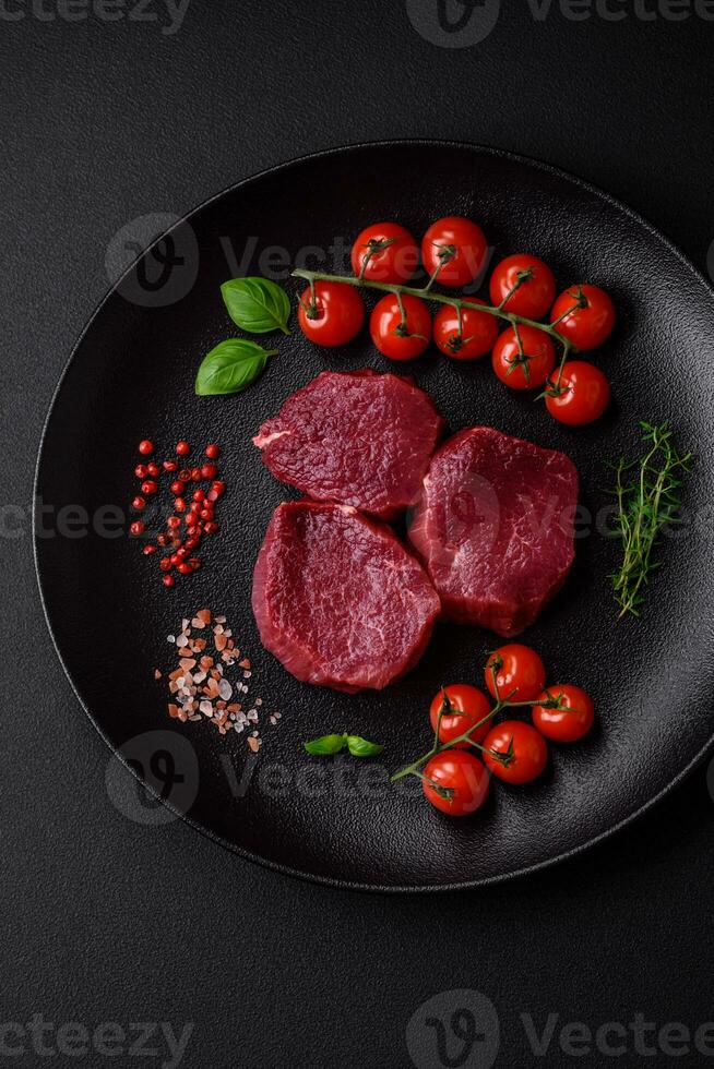 suculento cru carne com especiarias, sal e ervas em uma Sombrio concreto fundo foto