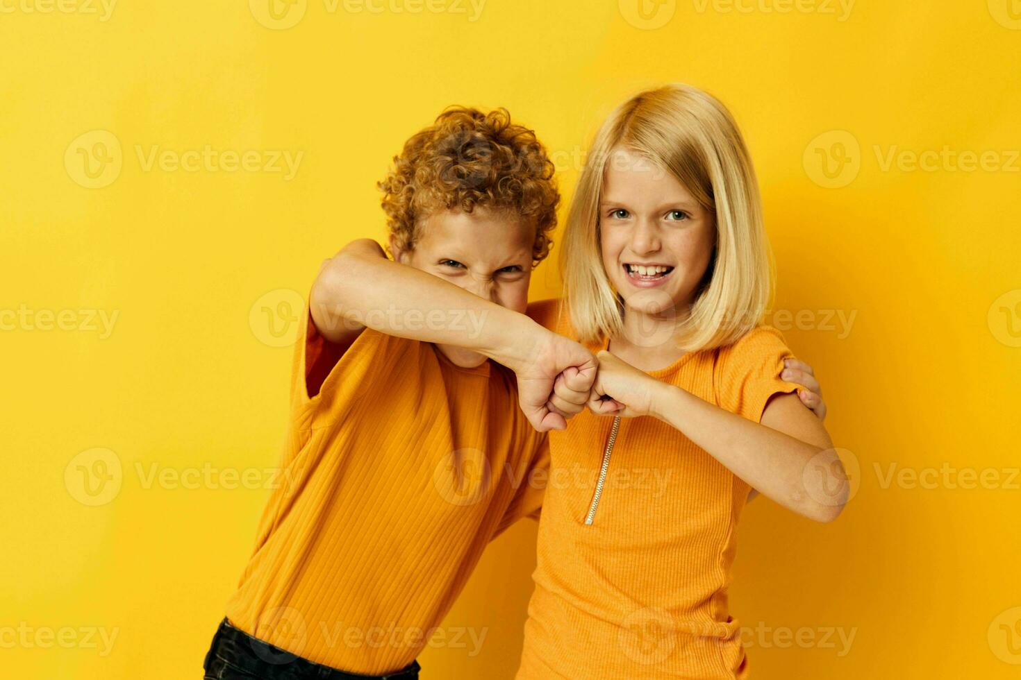 dois alegre crianças dentro amarelo Camisetas em pé lado de lado infância emoções amarelo fundo foto