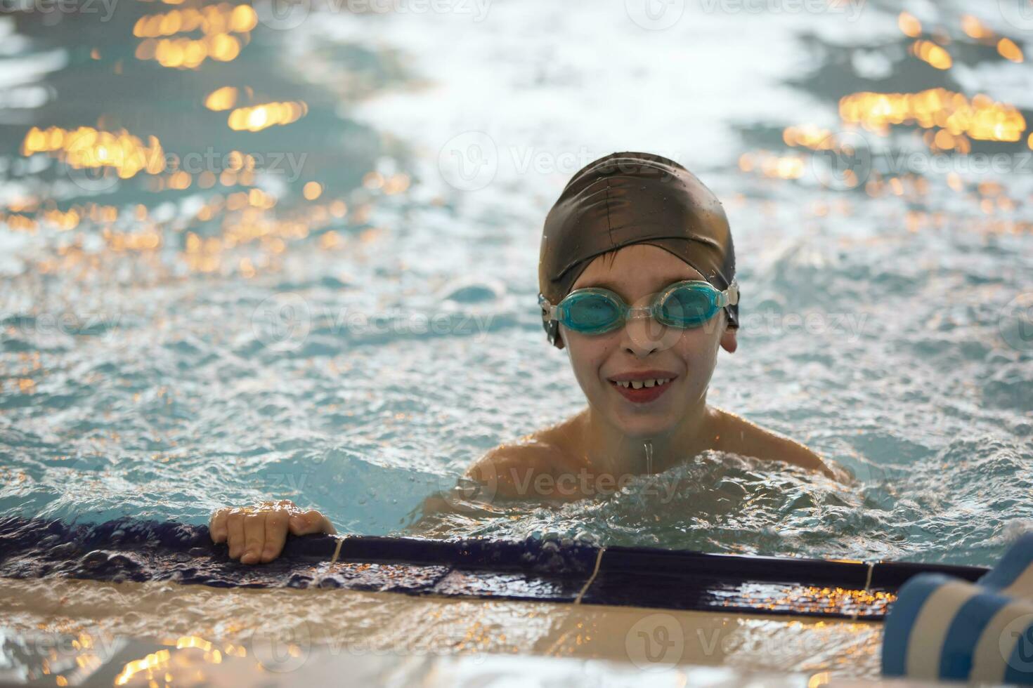 Garoto dentro uma natação boné e natação óculos dentro a piscina. a criança é acionado dentro a natação seção. foto