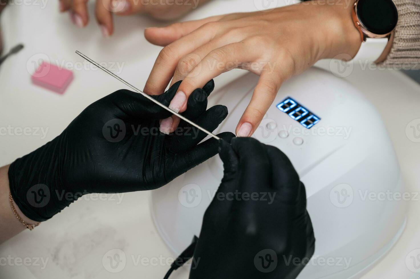 uma manicure mestre dá uma manicure para uma menina dentro a salão. unhas estão preenchidas com uma unha arquivo. fechar-se foto