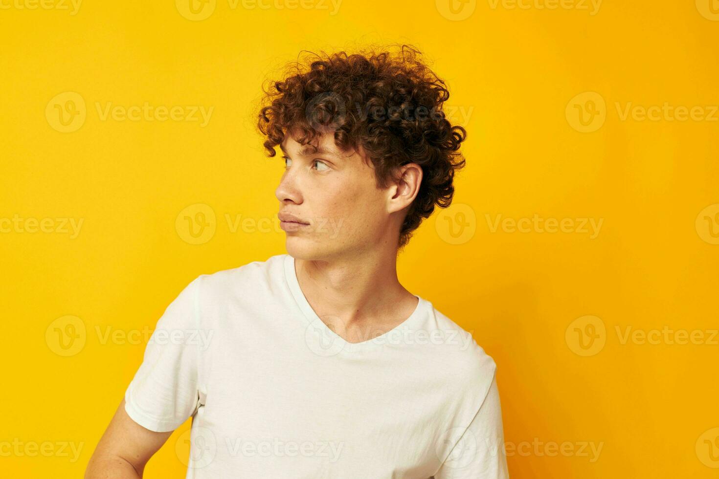 encaracolado ruivo cara dentro uma branco camiseta em uma amarelo fundo foto