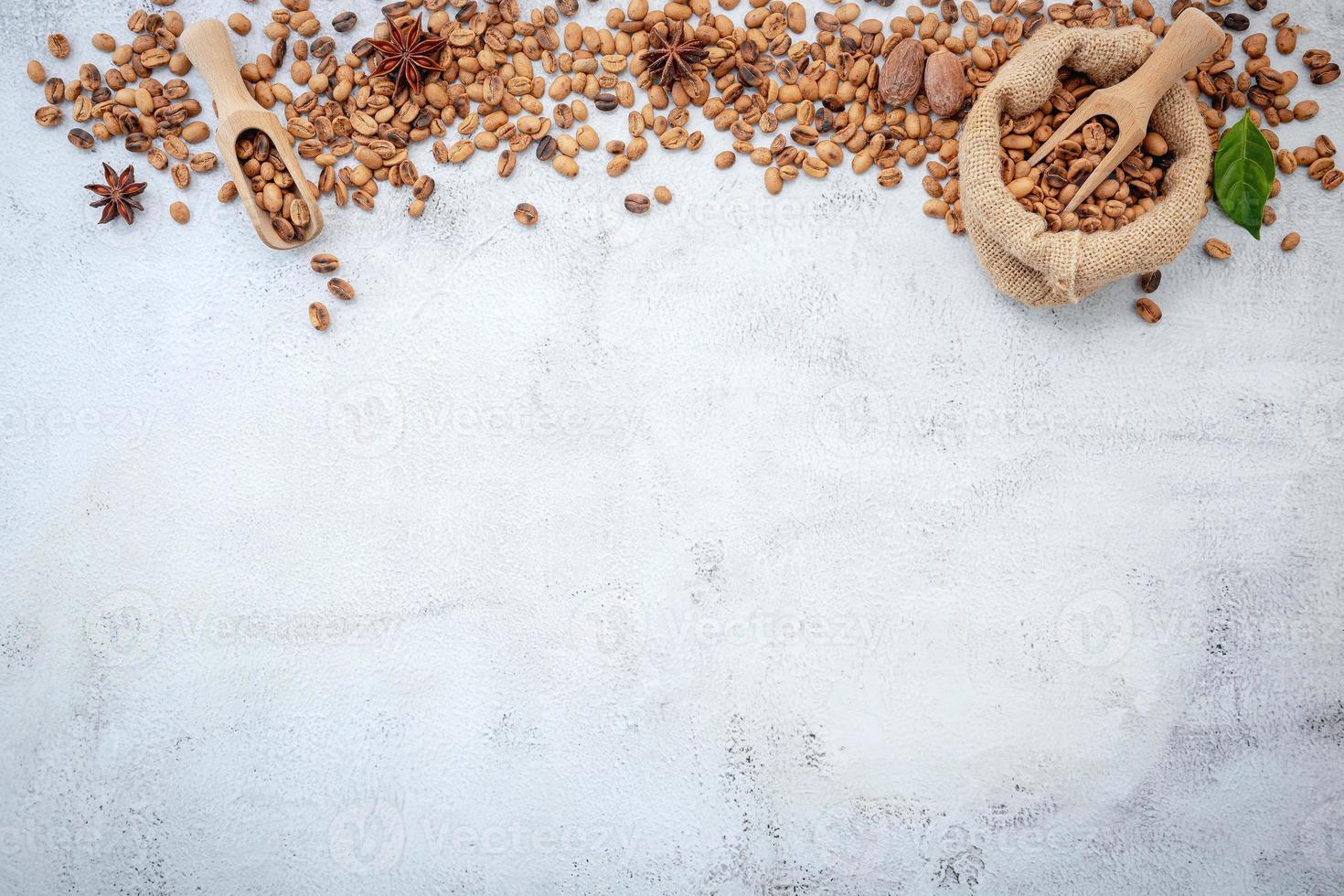 grãos de café torrados com colheres configuradas em fundo branco de concreto foto