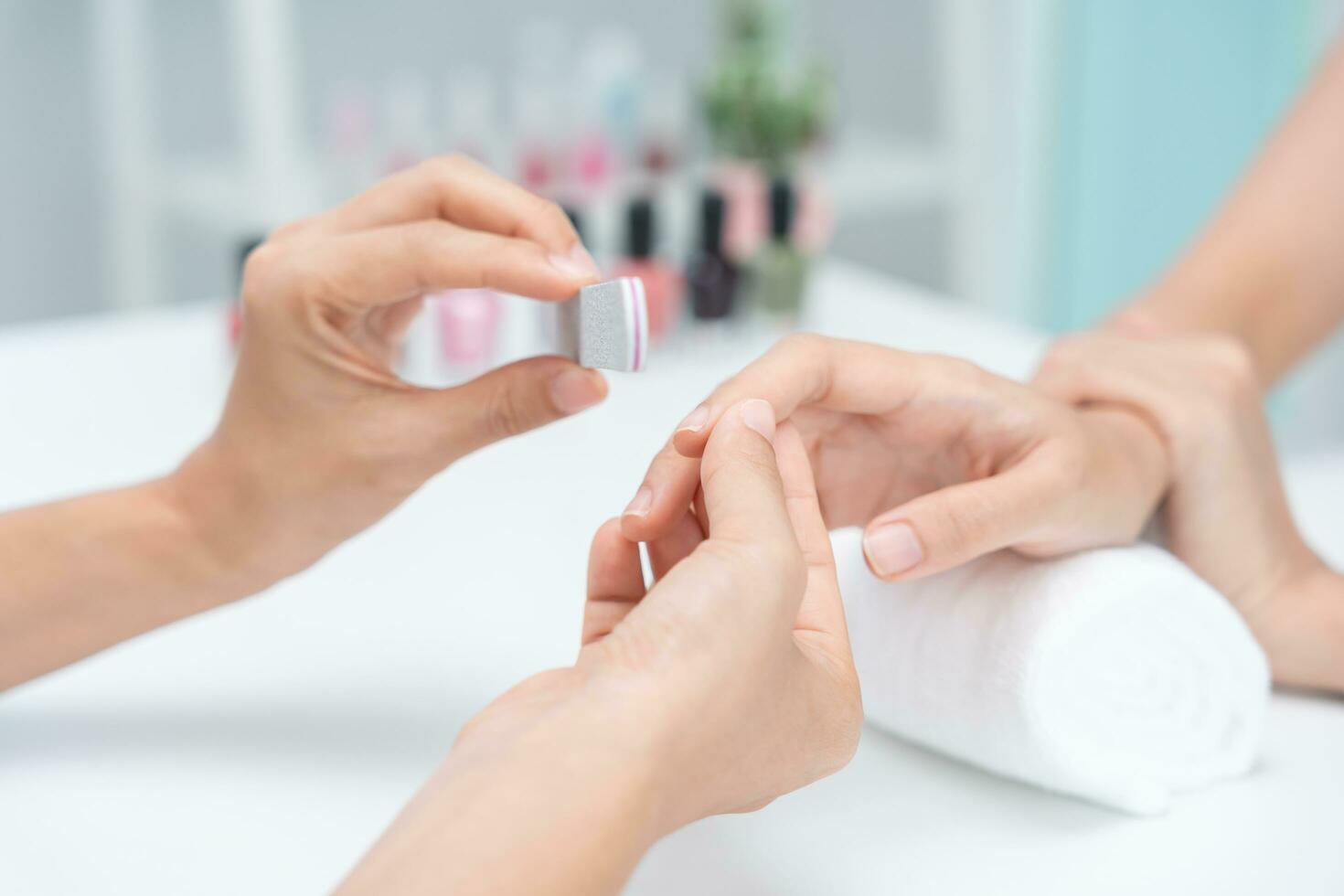 mulher recebe serviço de atendimento por manicure esteticista profissional no centro de spa. salão de beleza de unhas usa lixa de unha para tratamento de esmalte. manicure faz cliente de unha bonita. tratamento de spa para cuidados com o corpo foto