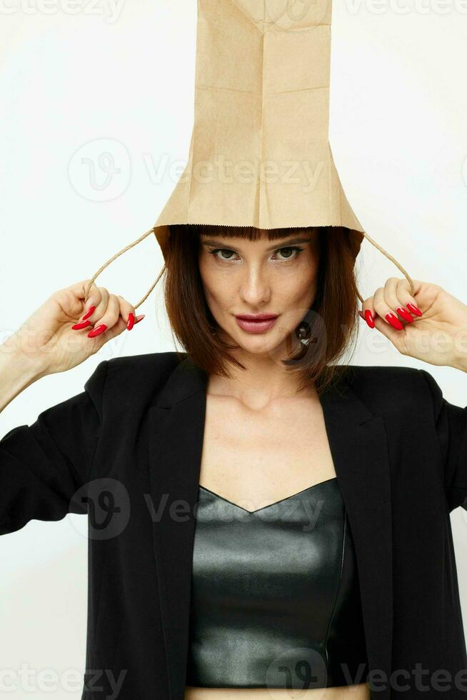 retrato do uma mulher dentro uma couro terno Preto Jaqueta com uma saco em dele cabeça luz fundo foto