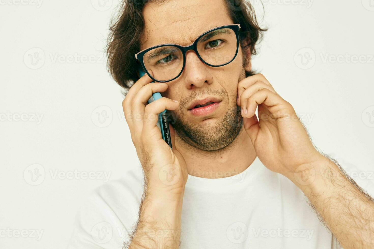 bonito homem dentro uma branco camiseta comunicação de telefone luz fundo foto