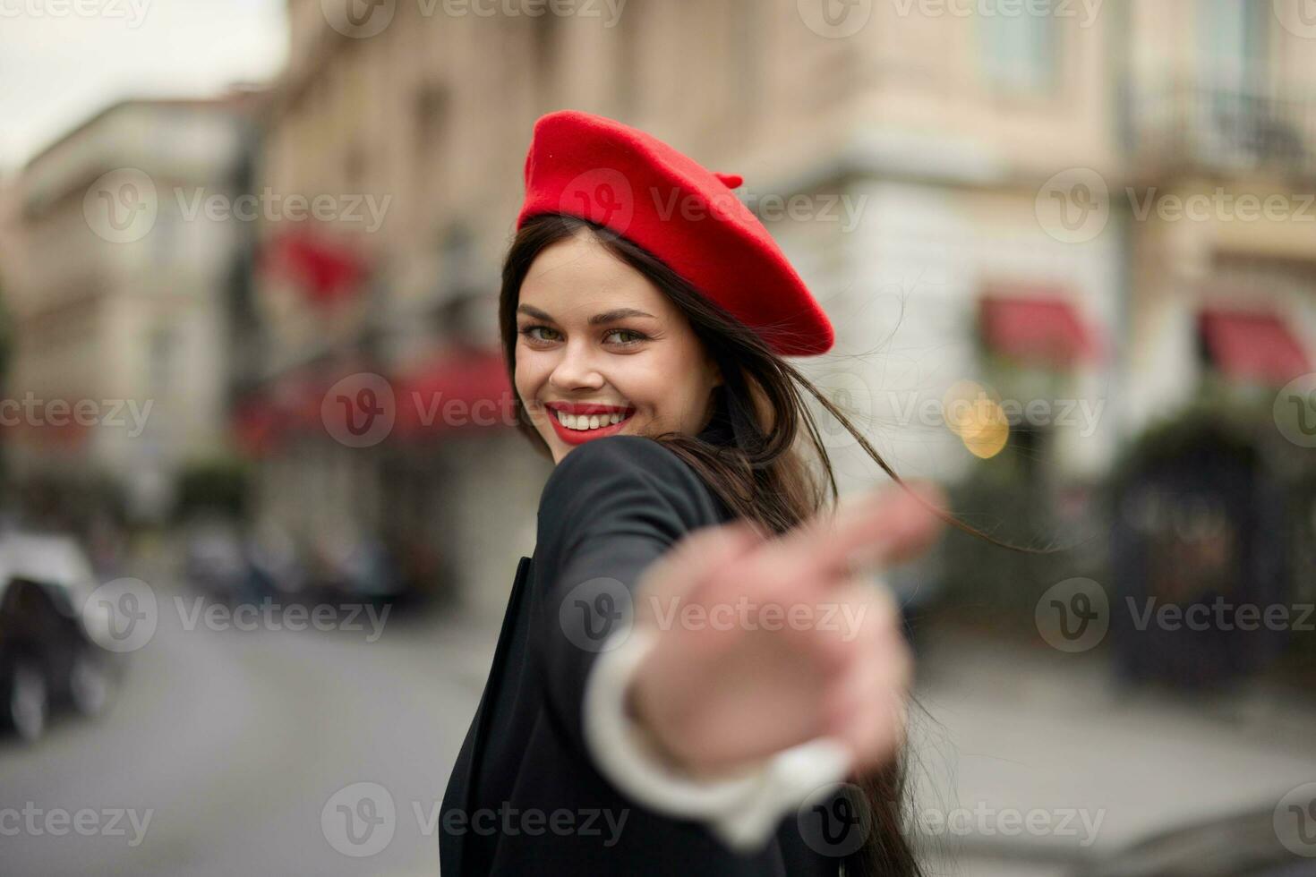 moda mulher sorrir com dentes em pé em a rua dentro frente do a cidade turista Segue mim à moda roupas com vermelho lábios e vermelho boina, viagem, cinematográfico cor, retro vintage estilo, urbano moda. foto