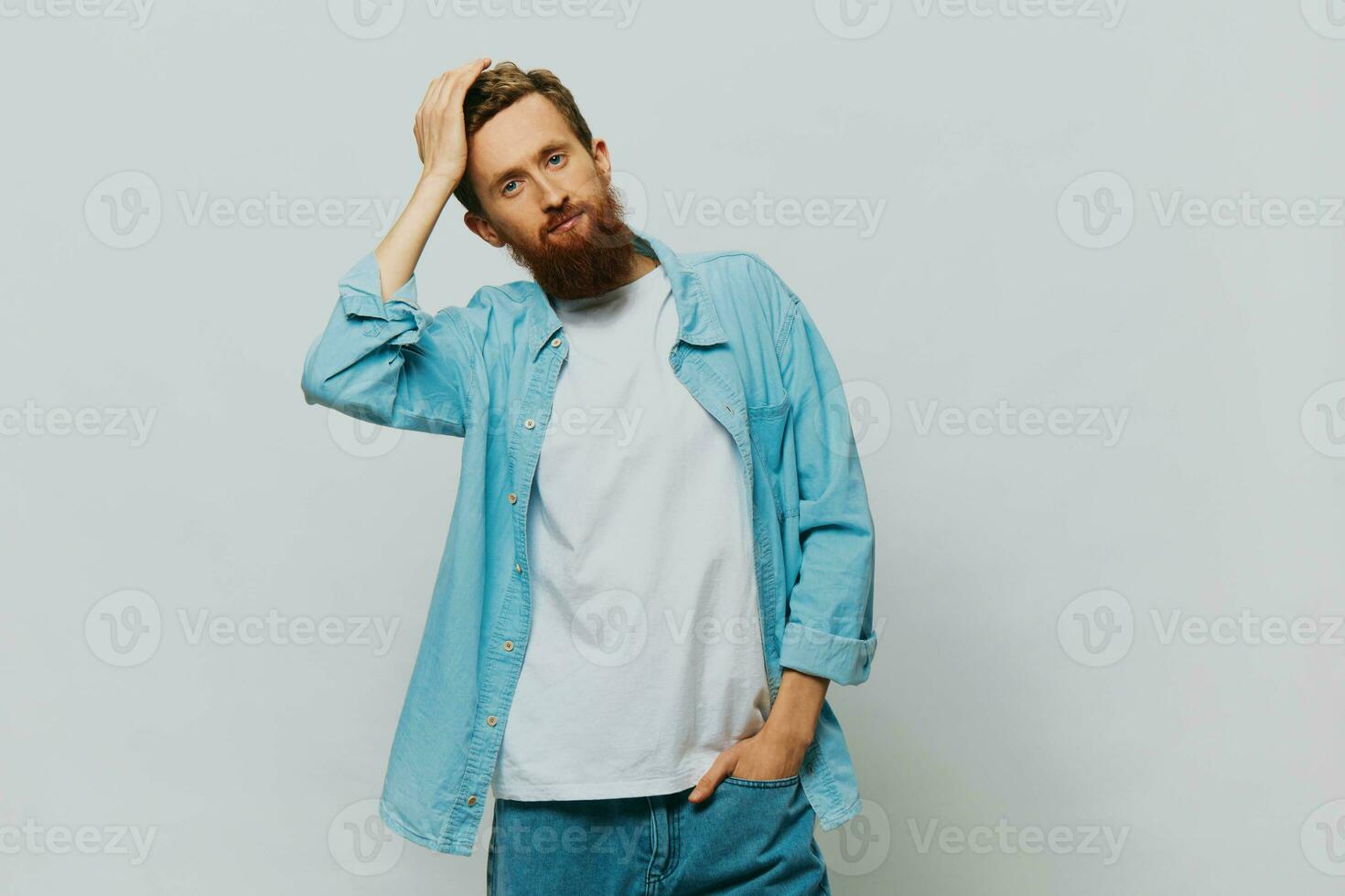 masculino hipster retrato sorrir em cinzento fundo dentro azul camisa e branco camiseta, retrato do uma homem com uma barba foto