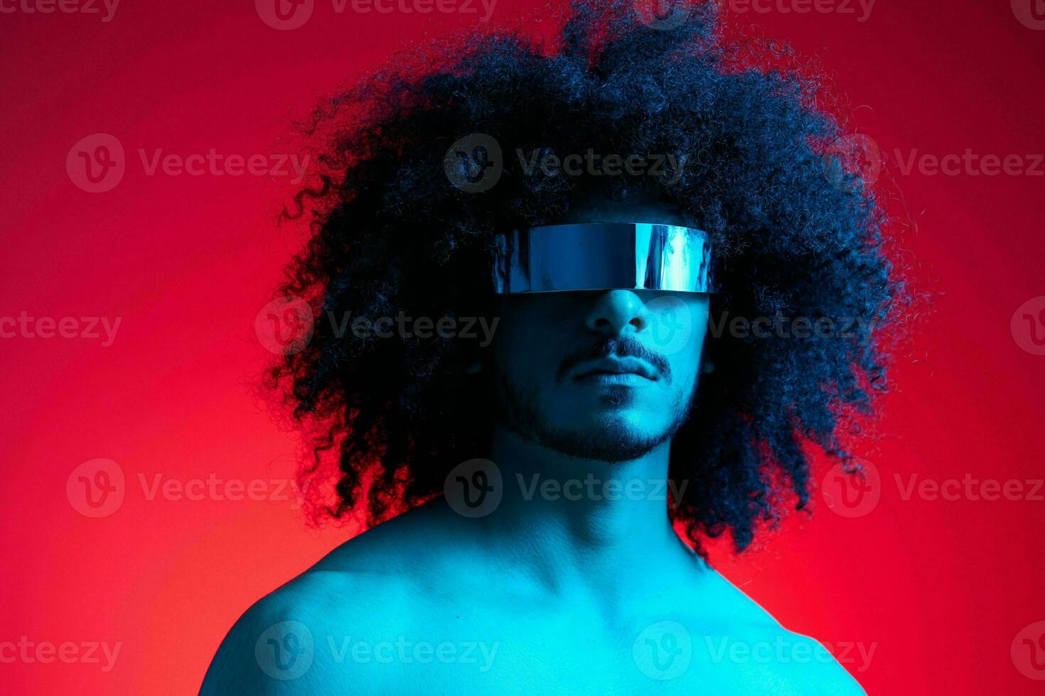 retrato do moda homem com encaracolado cabelo em vermelho fundo com à moda copos, multinacional, colori luz, Preto couro Jaqueta tendência, moderno conceito, sexy corpo. foto