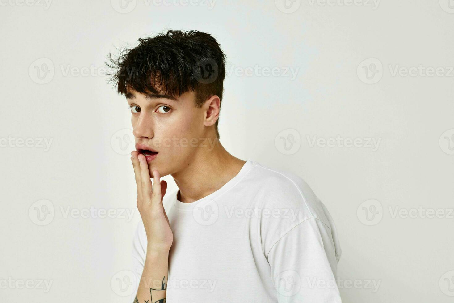 retrato do uma jovem homem moderno juventude estilo branco camiseta tatuagem em a braço luz fundo inalterado foto