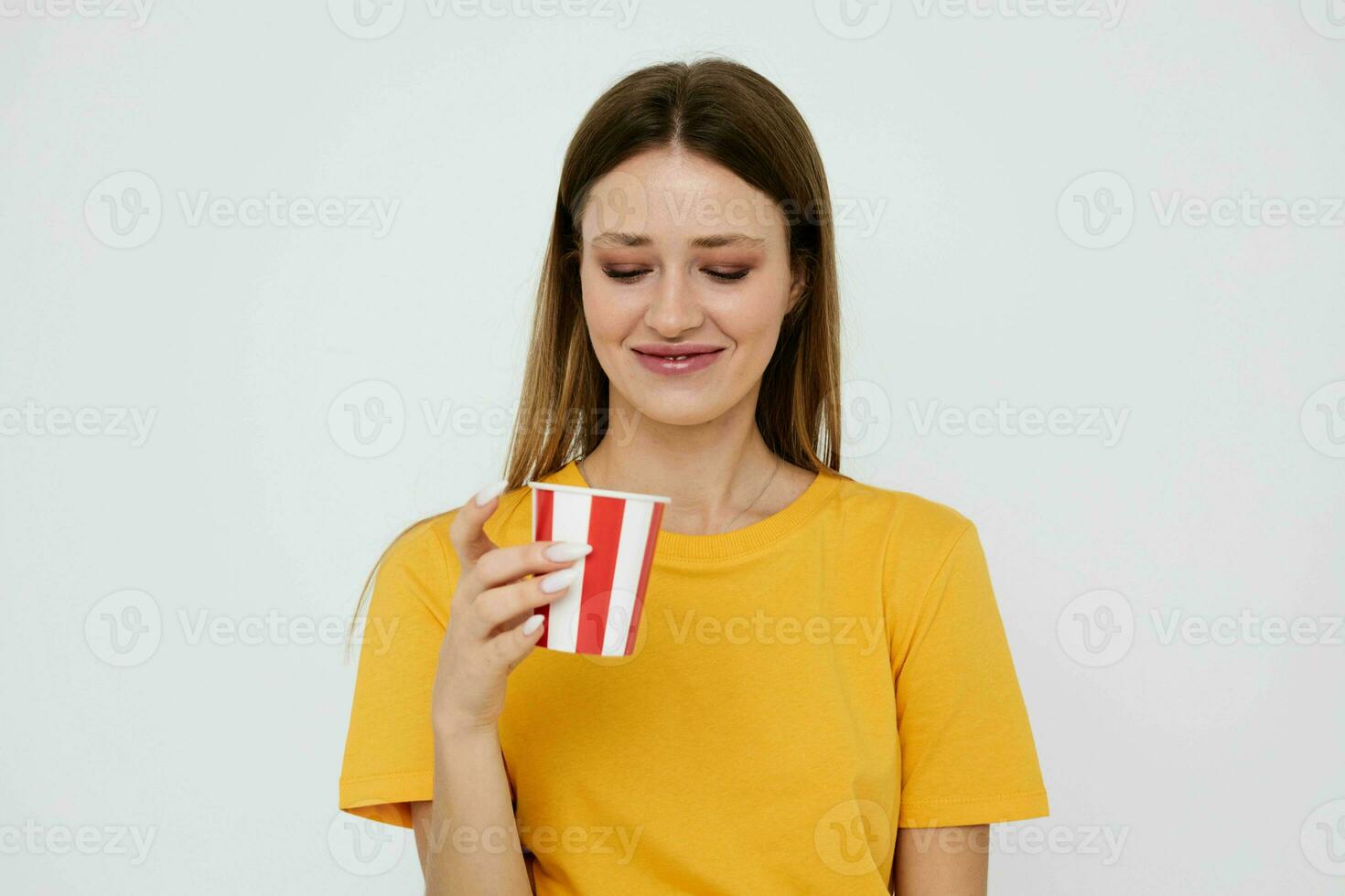 bonita mulher dentro amarelo camiseta vidro com beber foto