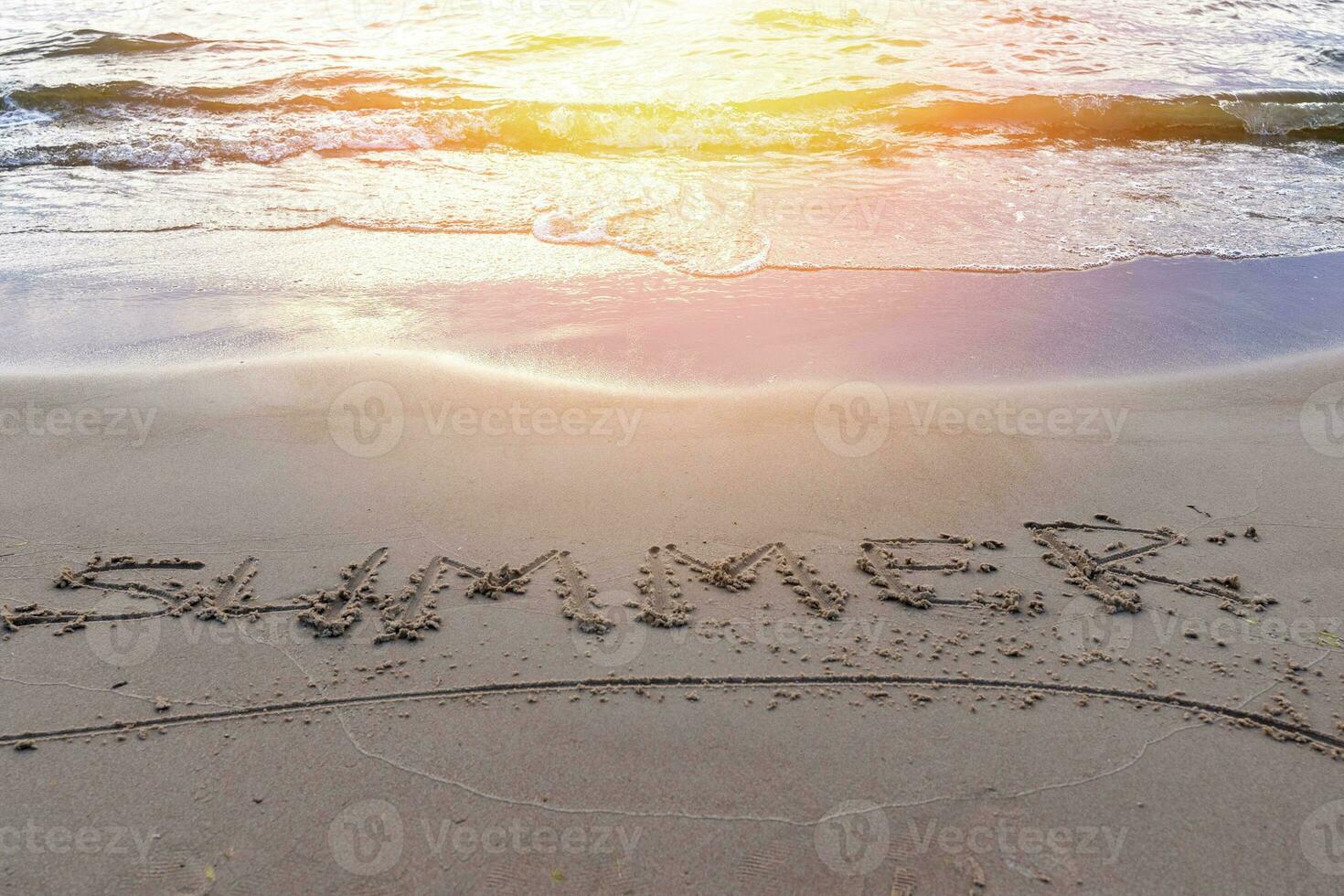 palavra verão em a areia em a mar arenoso de praia dentro a pôr do sol luz foto