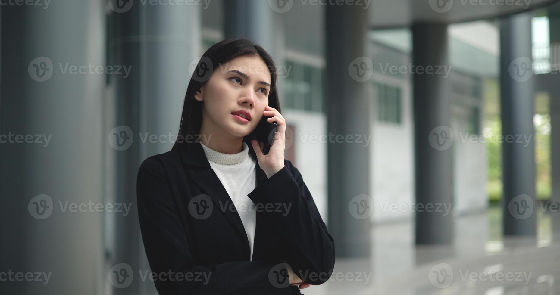 jovem ásia empresária dentro terno falando em Smartphone às moderno escritório foto