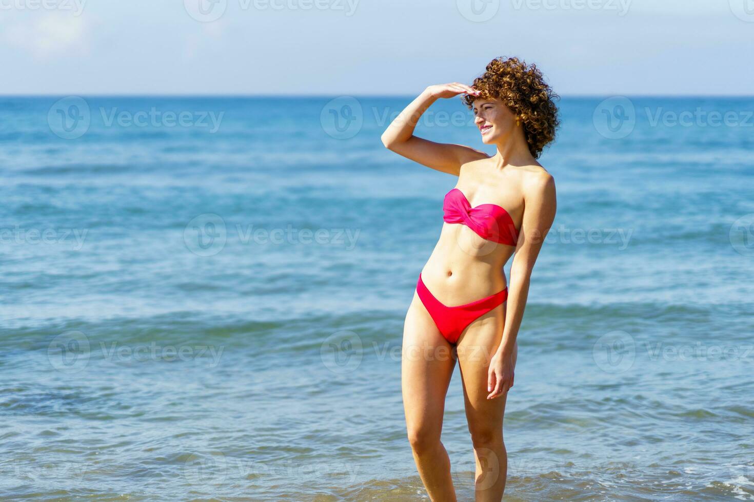 fino mulher dentro bikini em pé dentro água do mar foto