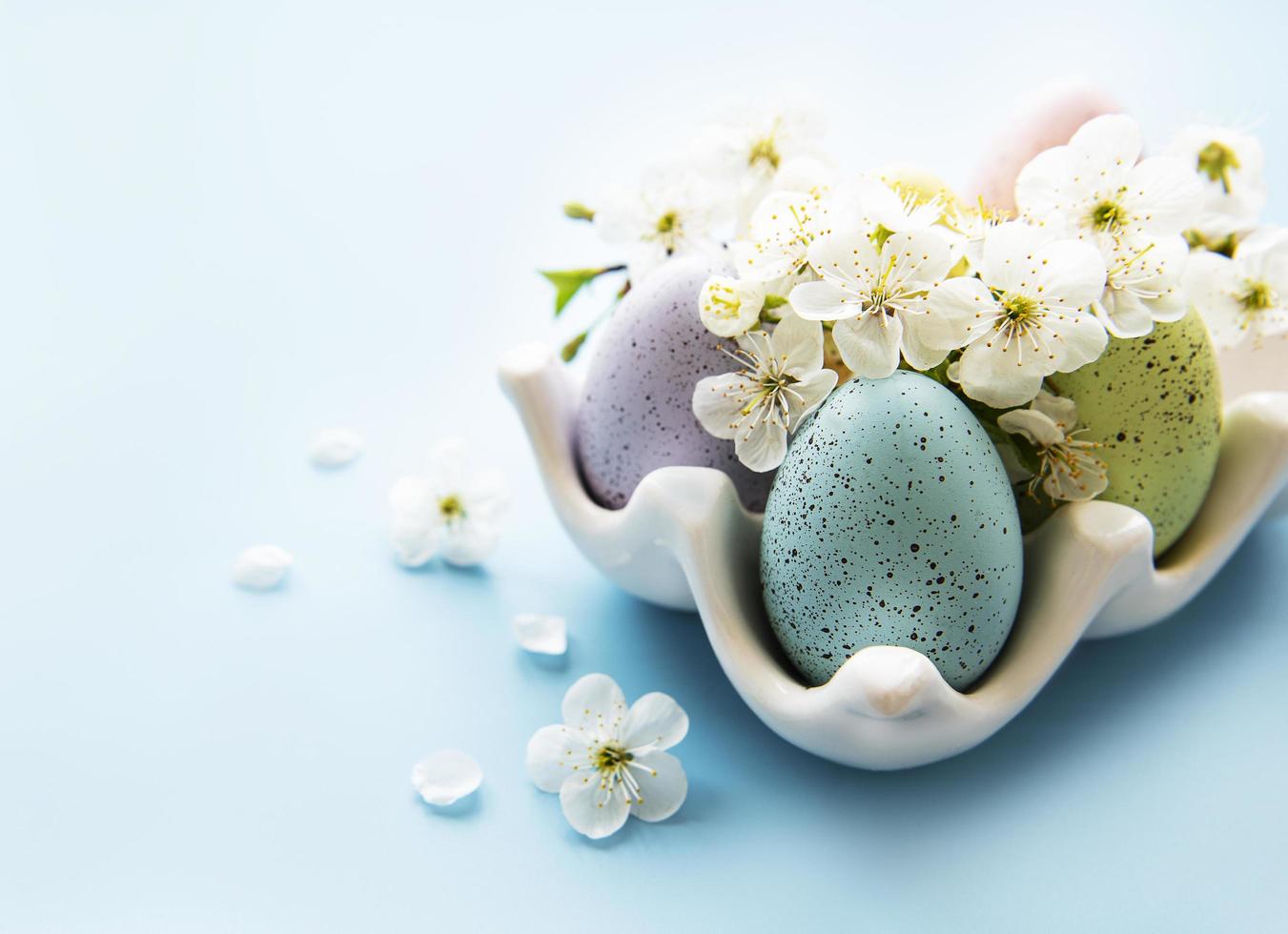 ovos de páscoa na bandeja de ovos e flor da primavera foto