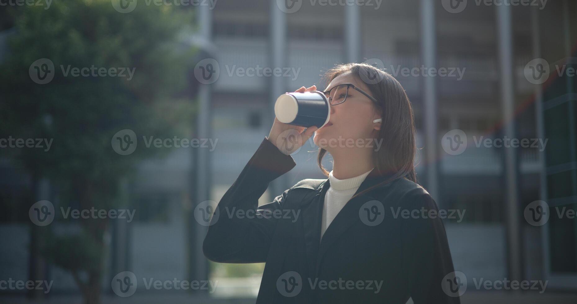 jovem o negócio mulher dentro formal terno segurando papel café copo bebericando café para relaxar às ao ar livre foto