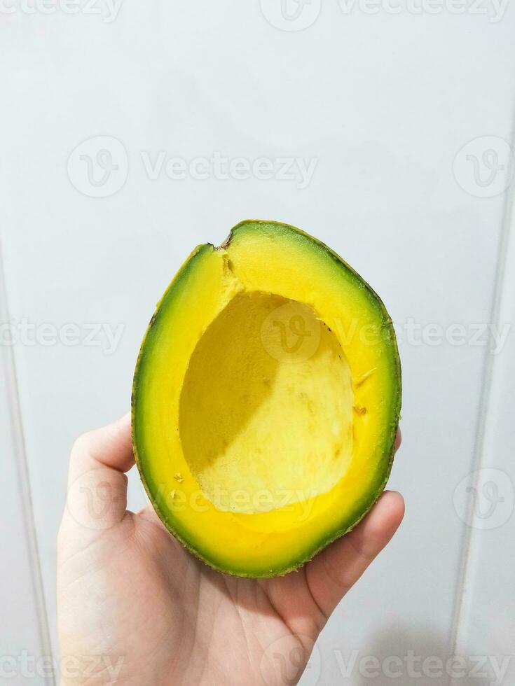 mão segurando uma fatia do abacate em uma branco fundo foto