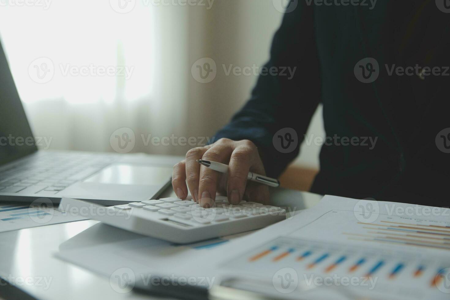 mulher empreendedora usando uma calculadora com uma caneta na mão, calculando despesas financeiras em home office foto