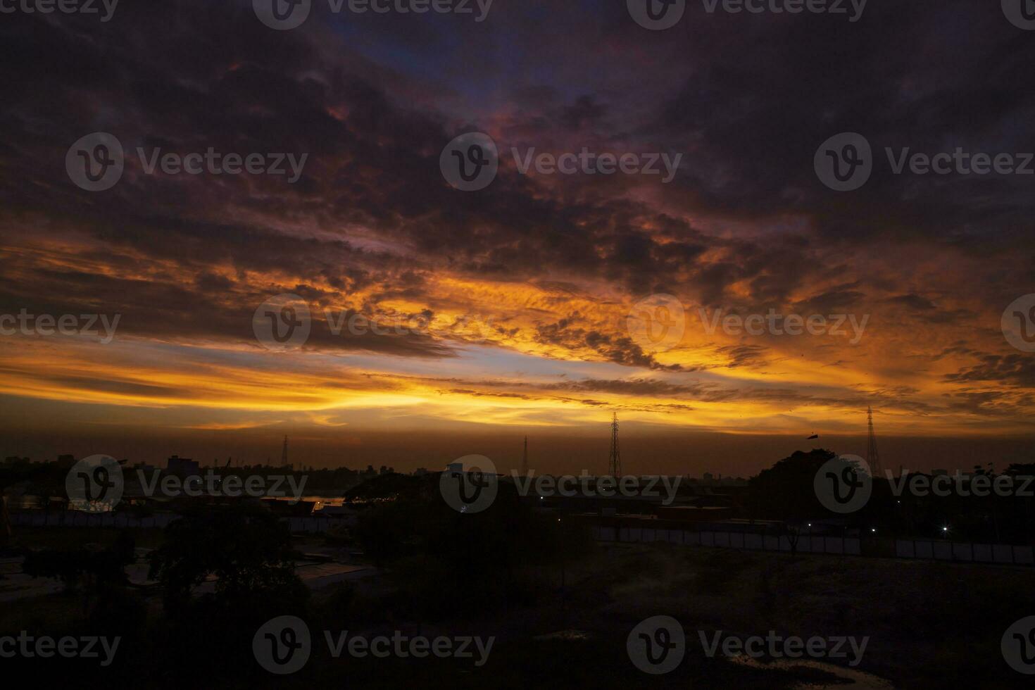 pôr do sol sobre a cidade, silhueta do uma Alto Voltagem transmissão torre foto