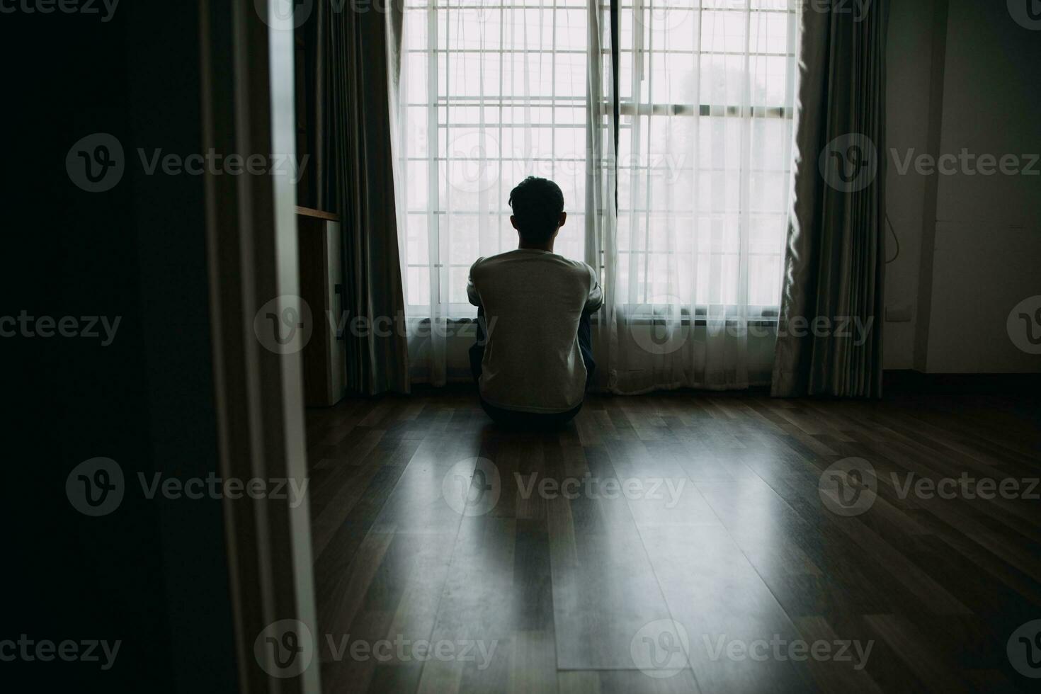 sozinho homem silhueta encarando às a janela fechadas com cortinas dentro quarto. homem carrinhos às janela sozinho foto