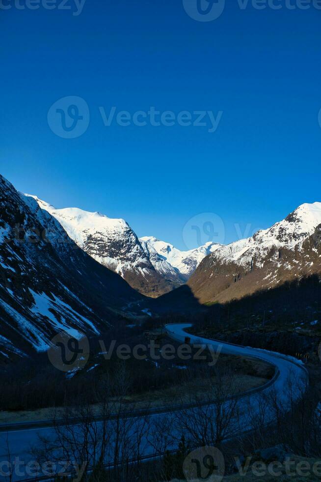 Visão entre montanhas dentro Noruega, através que uma estrada pistas. neve em a montanhas foto