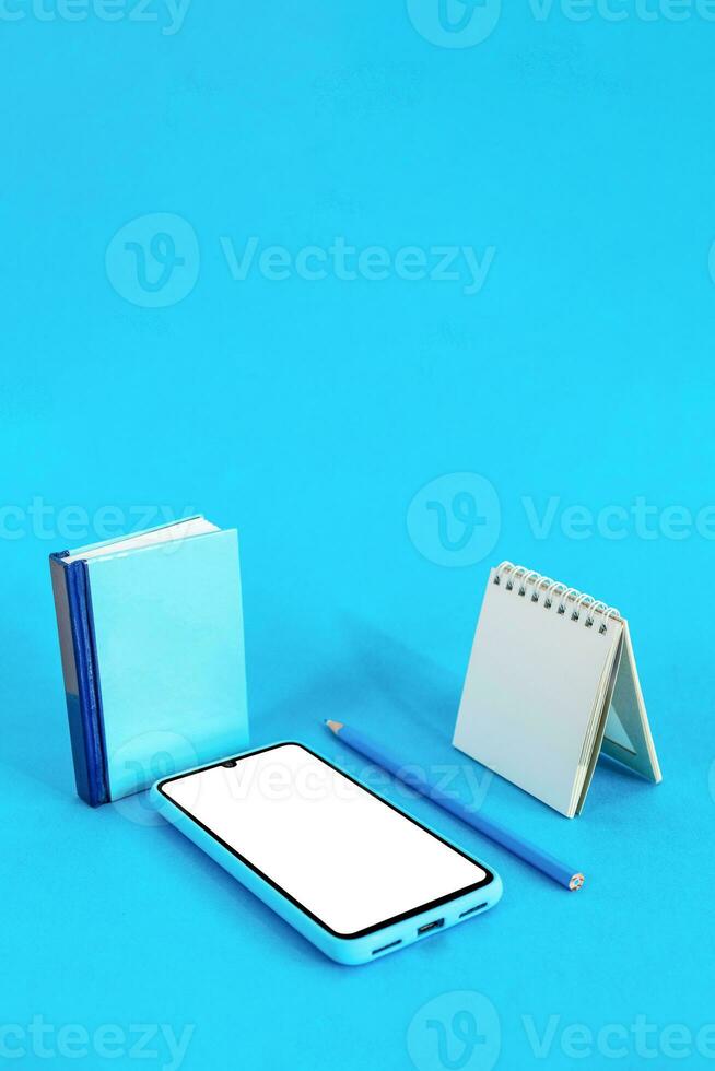 livro, lápis, caderno e inteligente telefone em azul fundo. Educação conceito. digital conectados Educação. foto