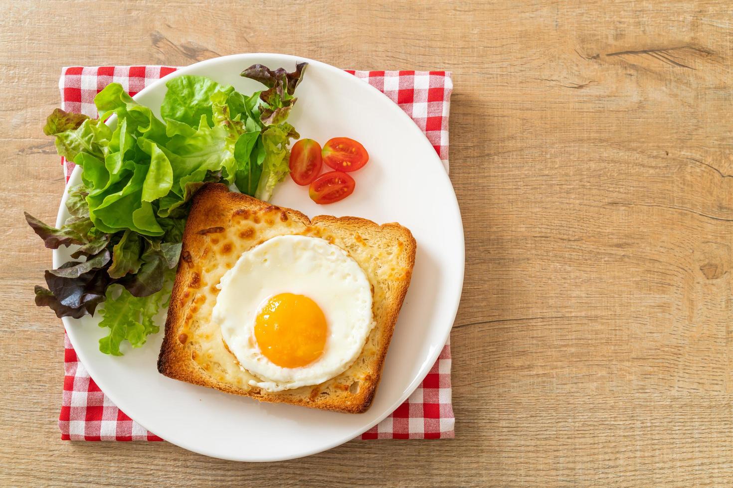 pão caseiro torrado com queijo e ovo frito por cima com salada de legumes no café da manhã foto