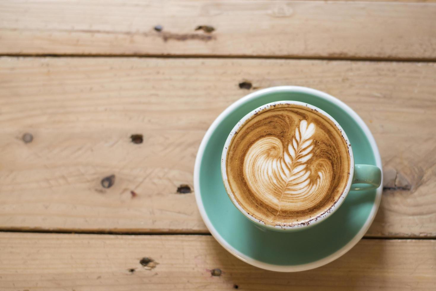 cappuccino quente com latte art em fundo de madeira foto